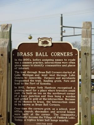 In the 1800s, before naming roads became common practice, intersections were often given names to designate settlements and landmarks.The trail through Brass Ball Corners started at Lake Michigan and went west through Lake Geneva to Janesville. Farmers and traders often walked along the trail, transporting grain, furs and lead to the port of Kenosha.In 1842, farmer Seth Huntoon realized the growing need for a place where travelers could relax. He built a hotel on the northwest corner of a busy intersection, and then hung a gilded wooden ball at the intersection. Because of its resemblance to brass, the intersection became known as Brass Ball Corners.Over time, the corners grew, as a school, a post office, a church, a shoemaker and several houses were built on the corner. The community eventually became the village of Paddock Lake. Today, a replica of a brass ball hangs nearby. Installed in 2005 by the Wisconsin Historical Society.