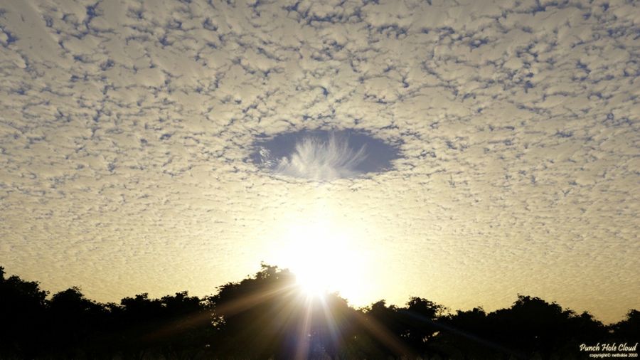 This rare effect can be seen in cirro-Cumulus clouds — large circular gap that is called a Fallstreak. Hole in the clouds caused by falling ice crystals.

Ice crystals can form in the higher clouds or the condensation trail of the aircraft flown. Usually they are produced by the plane passing through such a cloud layer. In this case, if the air has a suitable temperature and moisture content, the falling crystals will absorb water from the air and grow.

For this to happen, the water must be so cold that freezing it needs only a suitable surface. Loss of moisture in the air increases the evaporation rate of water droplets in the cloud, and they are scattered, forming a hole.
Translated by «Yandex.Translator»