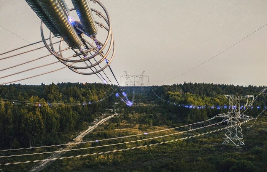 Corona discharges at 750 kV overhead line phases in the zone of interaction with 330 kV overhead line passing from below.Author: Glib Lanovenko