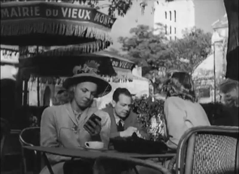 Fotograma de la película.Una chica en una mesa de café con un dispositivo de información portátil