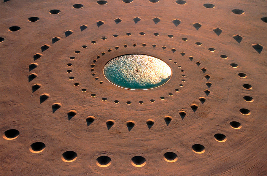 Name: art-project "breath of the desert" ("Desert Breath" Land Art project)

Author: DAST. Arteam. Danae Stratou (installation artist), Alexandra Stratou (industrial designer &amp; architect), Stella Konstantinidis (architect)

Year of establishment: the project was completed in 1997

Description: Konstrukcija consists of 8,000 cubic meters of sand, having the form, creating precise positive and negative conical volumes. They form two intertwined spirals emanating from a common center with a phase difference of 180° in the same direction of rotation. The center is a vessel with a diameter of 30 m W-shape and filled with water. 

Location: the Art object occupies an area of 100.000 m2 in the Eastern Sahara desert bordering the Red sea in El Gouna, Egypt.

Coordinates: 27°22'52" N. lat. 33°38' e
Translated by «Yandex.Translator»