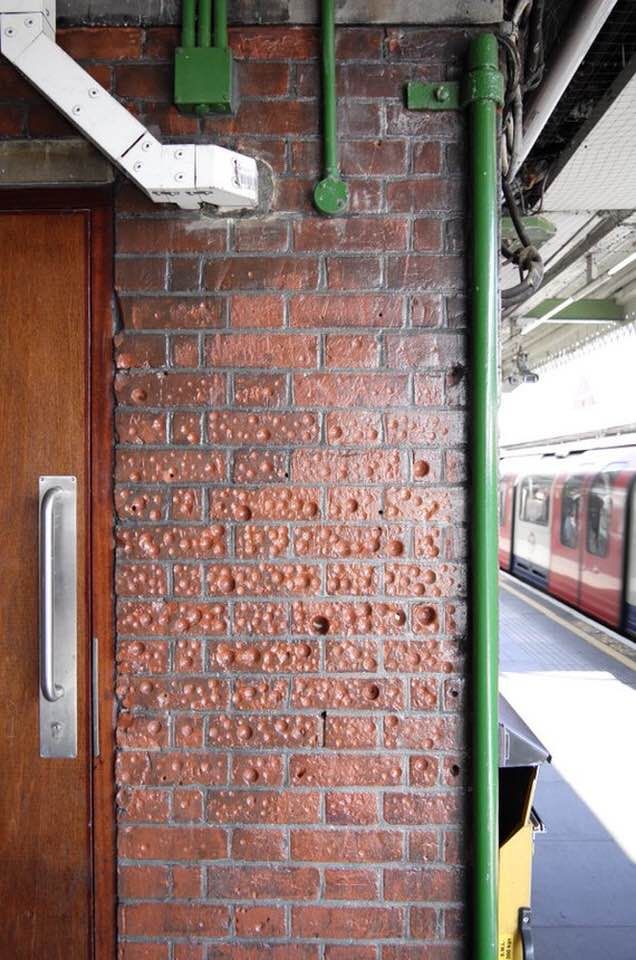 At one of the London train stations there is such a brick wall with depressions. While people were waiting for the train, they made such indentations with coins out of boredom. Such entertainment appeared somewhere in the 50s.