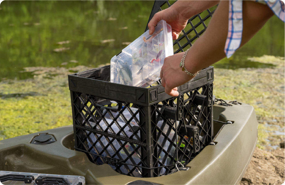 UbeCube CrateWhite PaddleOn Starter mounted on a kayak with the lid open as tackle boxes are placed inside.