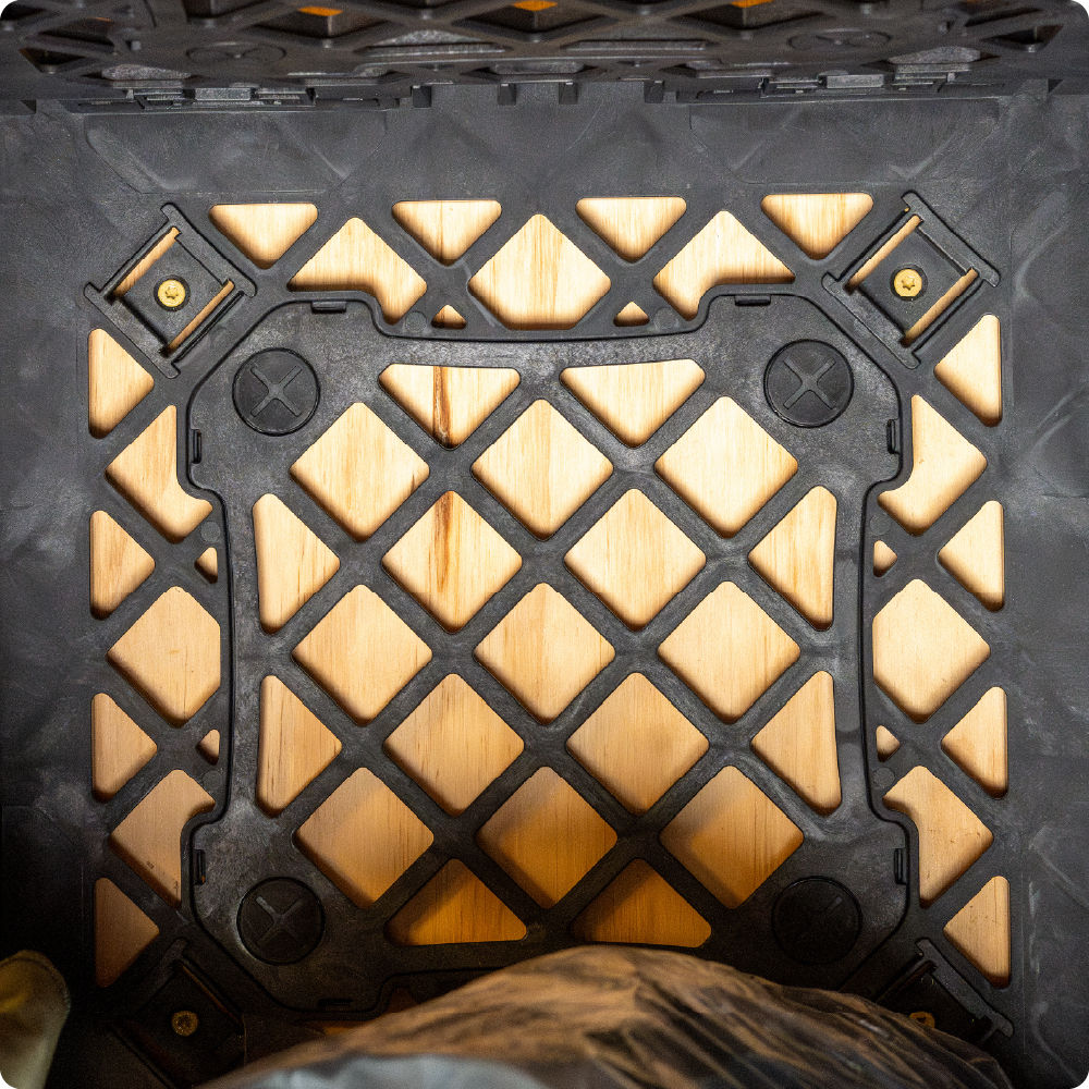 Interior view of a black UbeCube crate secured to a wooden wall using Screw Clips mounted through the crate’s open grid