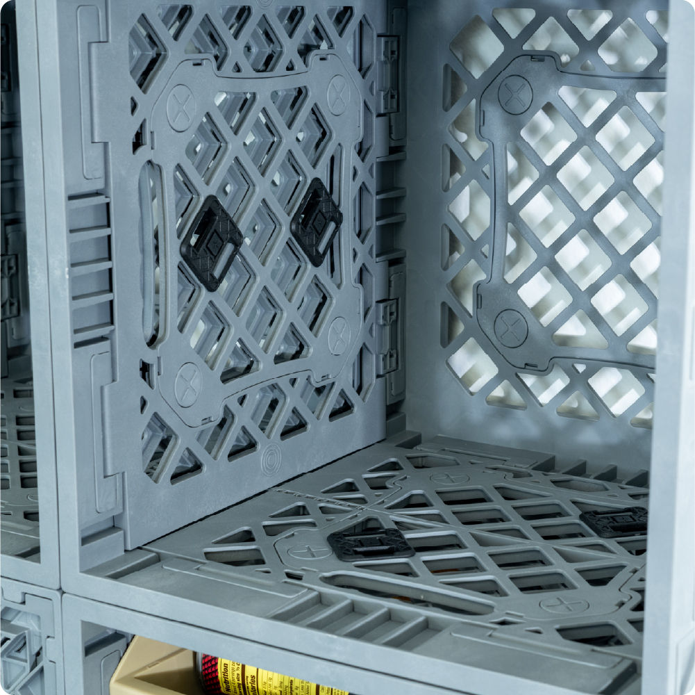 Close-up of black Snap-Fit Connectors installed through the side grid of a gray UbeCube crate to connect it to a crate below and to the side.