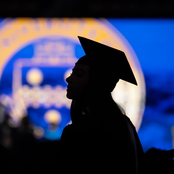 Silhouette of a graduate at a Pitt commencement ceremony.