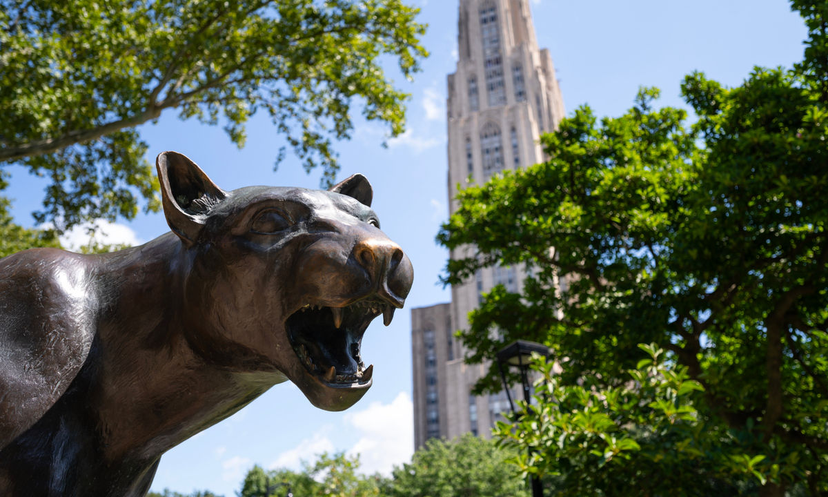 The Pitt Panther statue on campus with the Cathedral of Learning in the background.