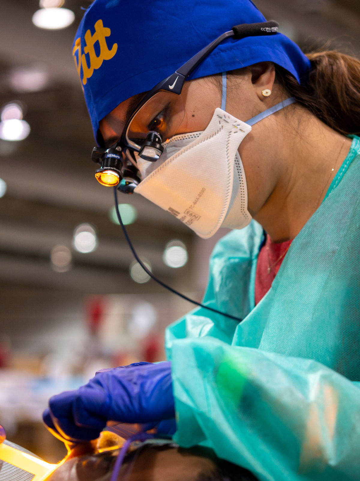 A dental student wearing a mask, and gloves performing a procedure.