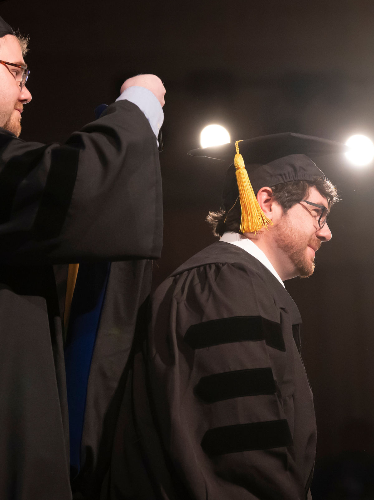 A faculty member placing a doctoral hood on a graduate during a commencement ceremony.