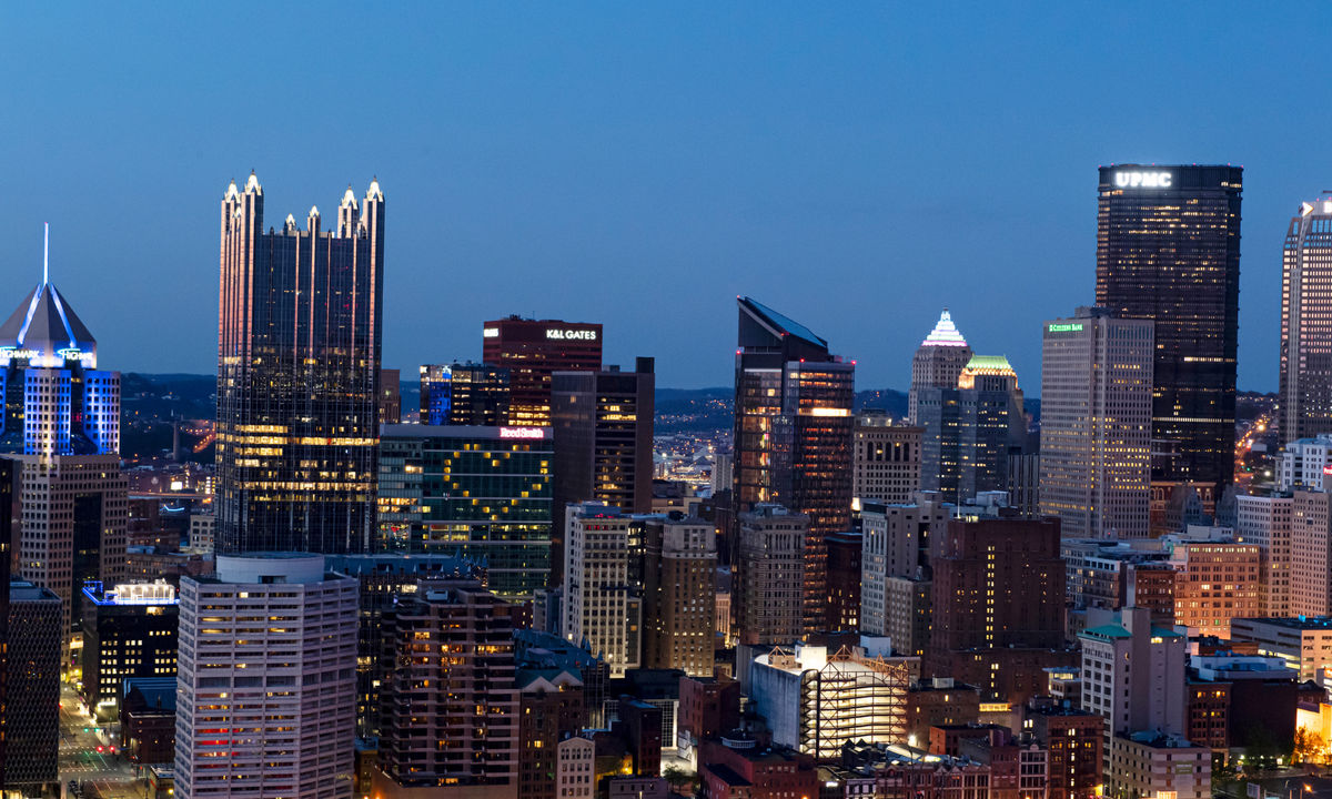 The Pittsburgh skyline at dusk with city lights illuminated.