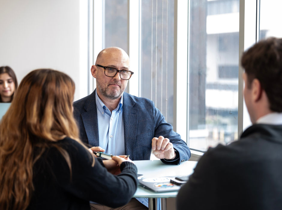 Three people in a discussion at a table in a professional setting.