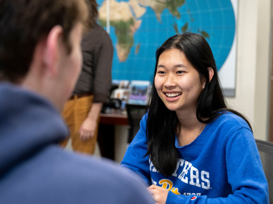 A smiling student in conversation with a classmate.