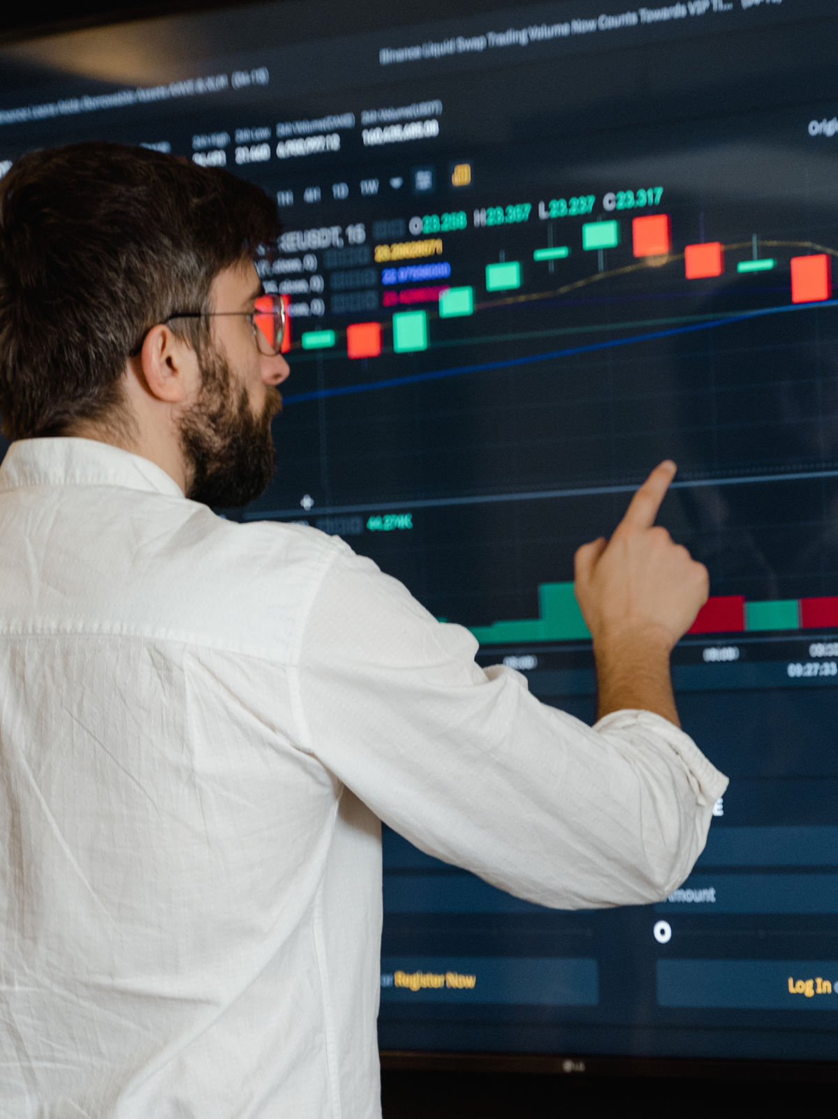 A person pointing at a large screen displaying a data chart.