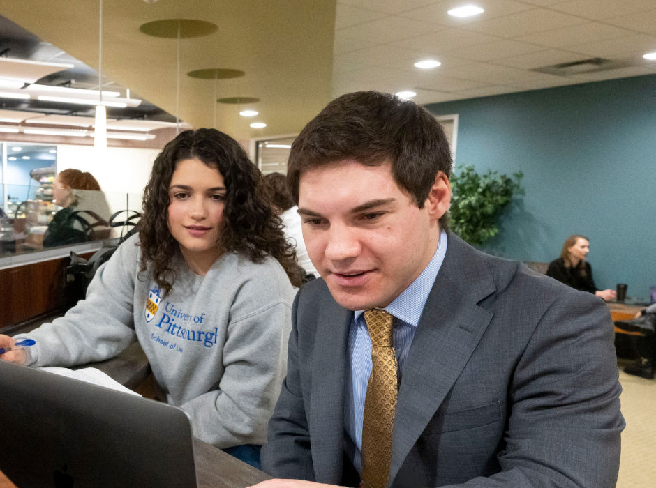 Two students looking at a laptop in a campus common area.