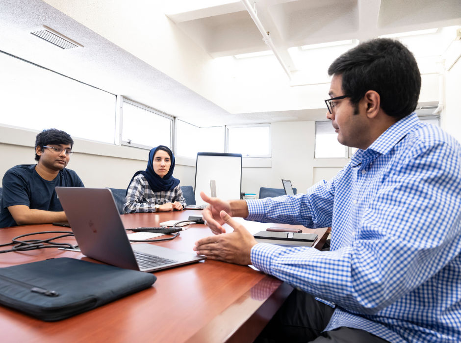 Dr. Kaushik Seshadreesan working with students in the Information Sciences building.