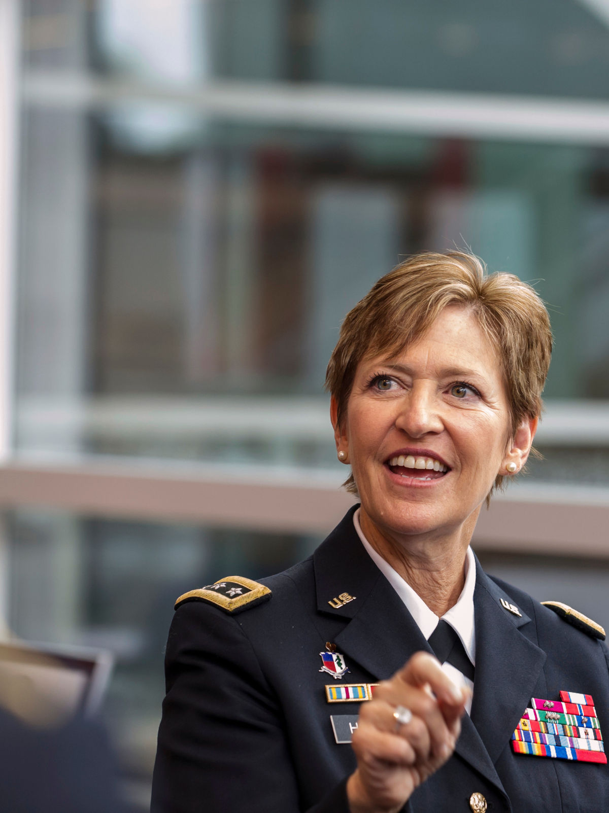 A smiling U.S. Army officer in dress uniform on a university campus.