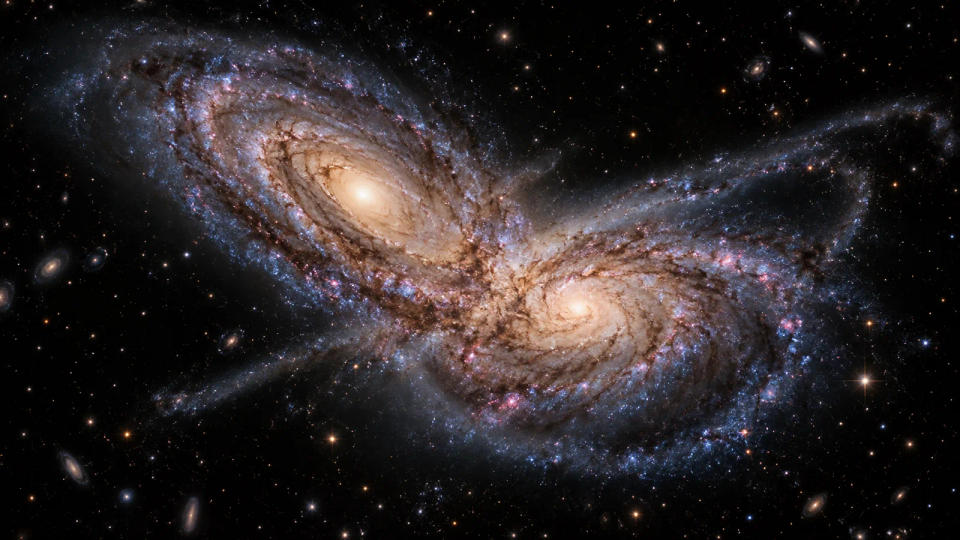 Two spiral galaxies overlapping during a close encounter, with distorted arms and tidal streams of stars and dust.