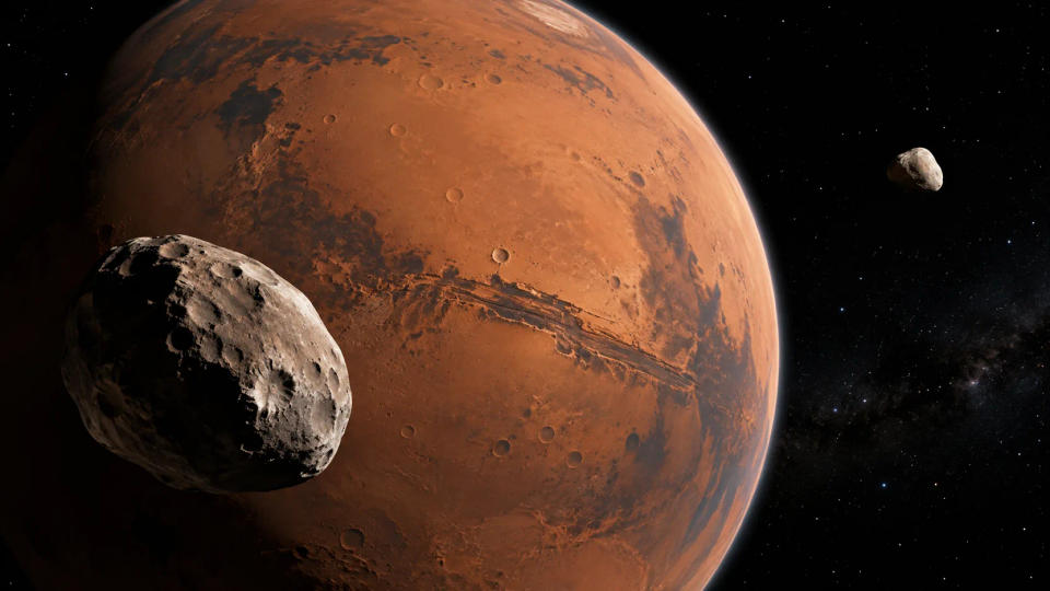 Mars seen from space with irregular Phobos in the foreground and smaller Deimos farther away.