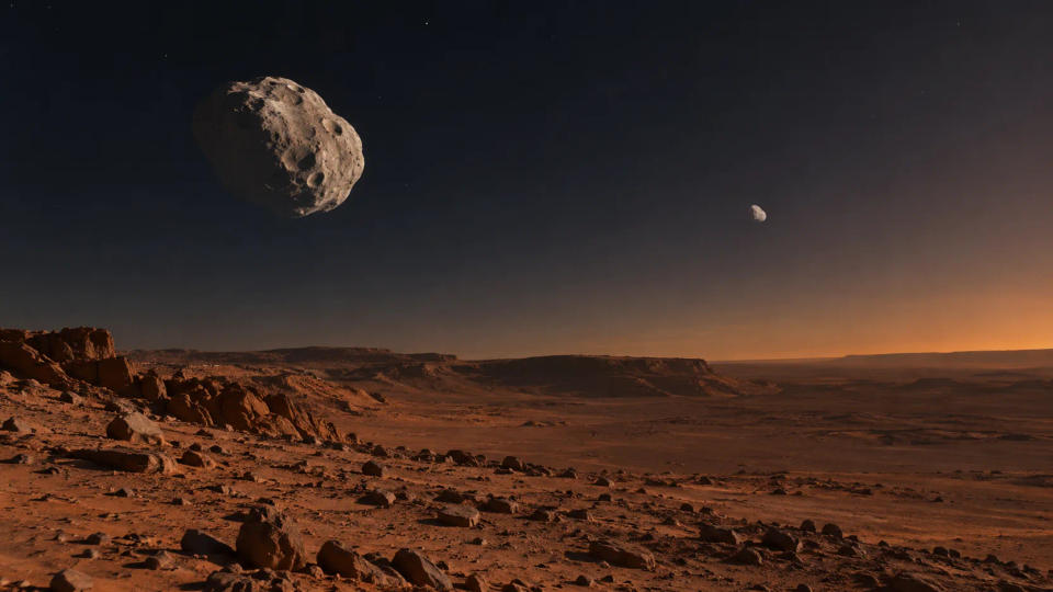 A Martian landscape beneath Phobos and Deimos, showing the larger irregular Phobos and much smaller distant Deimos in the sky.