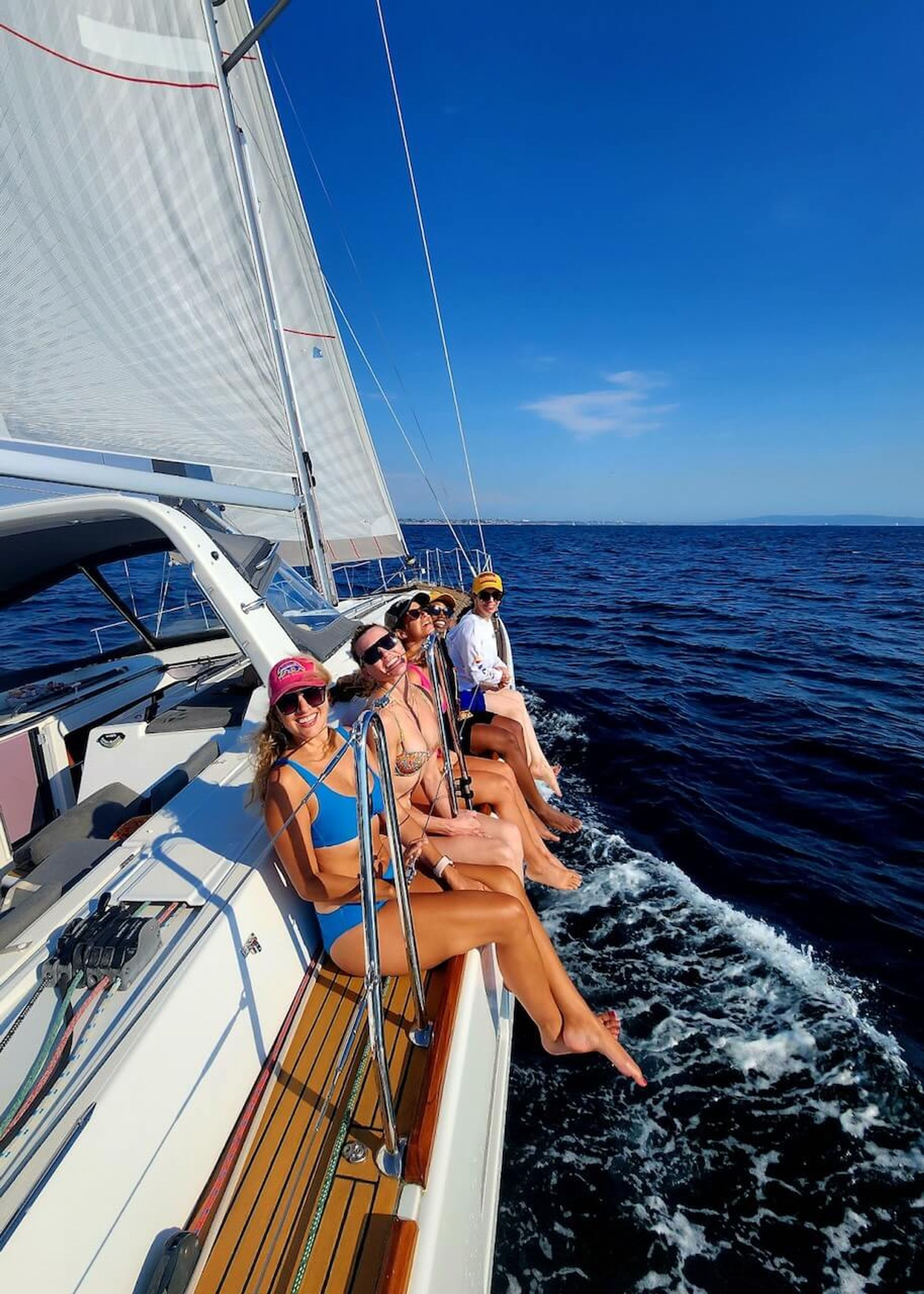 Group of friends sitting on the site of a sailboat while on a boat charter in Marina del Rey Group of friends sitting on the site of a sailboat while on a boat charter in Marina del Rey