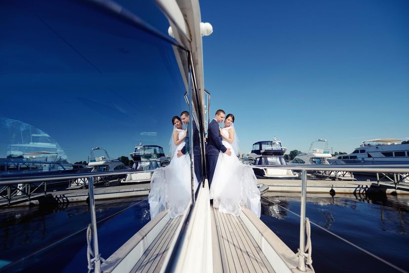 Wedding couple hugging on yacht, bride in dress and groom in suit Wedding couple hugging on yacht, bride in dress and groom in suit