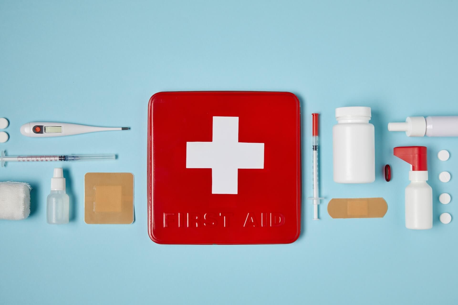 Top view of red first aid kit box on blue surface.