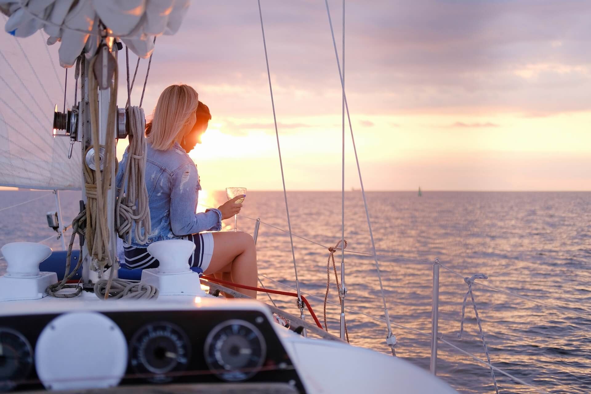 Two joyful women are celebrating good summer day at the yacht while watching beautiful sunset