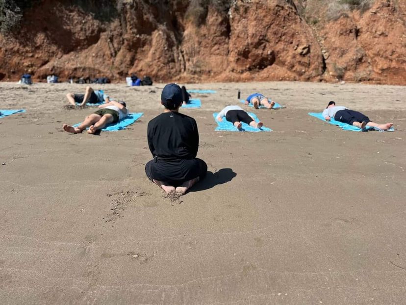 Yoga instructor leading a class on the sandy beach beside a yacht Yoga instructor leading a class on the sandy beach beside a yacht