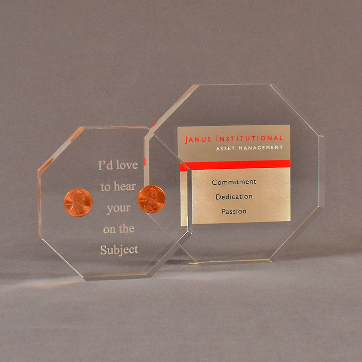 Two octagon acrylic embedment awards one with cast pennies the other with cast printed Janus Institutional Assets tagline.