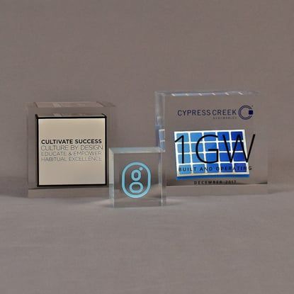 Three cube shaped acrylic embedment awards showing clarity of cast objects into crystal clear acrylic.