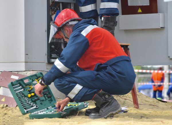 Electrician working with tools near electrical panel
