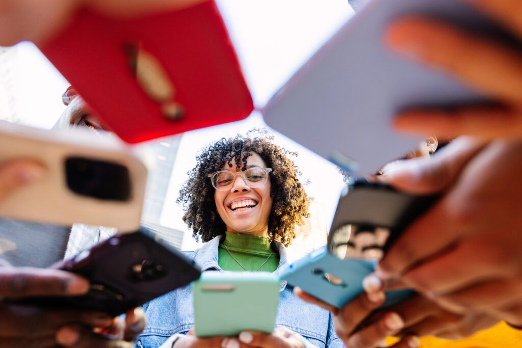 Group of friends smiling at smartphones.