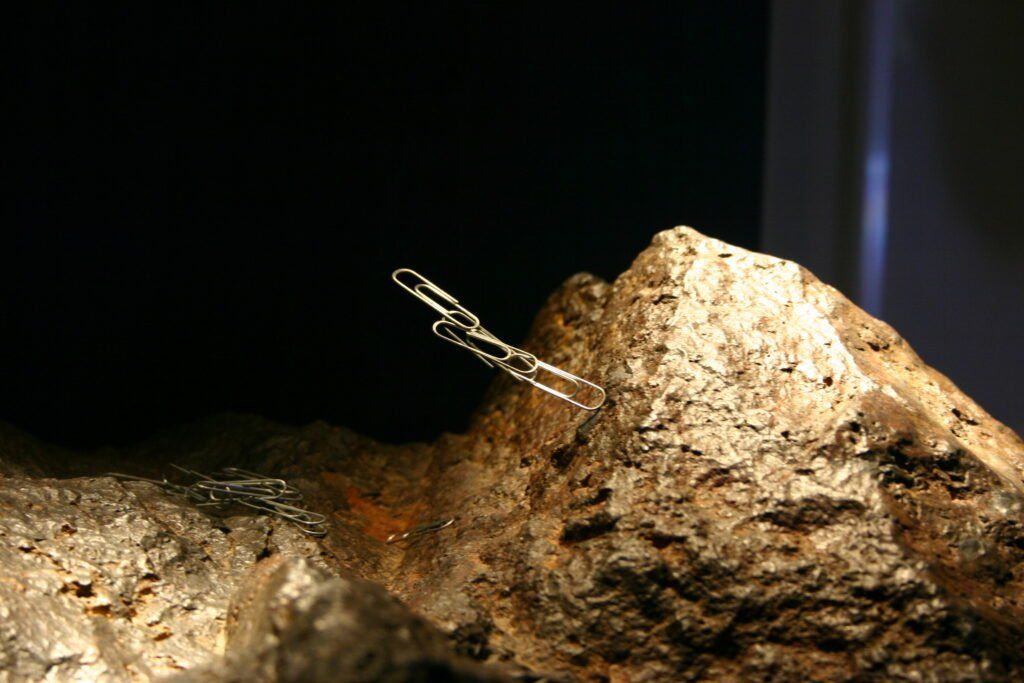Paperclip on magnetized metallic rock surface.
