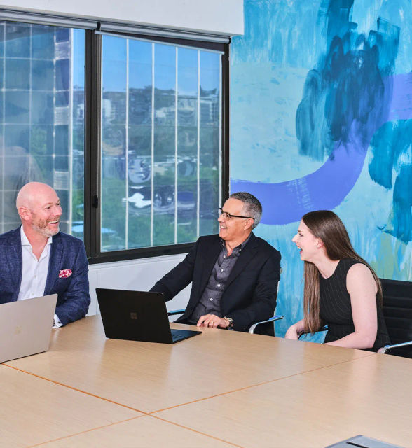 Three people with laptops having a meeting