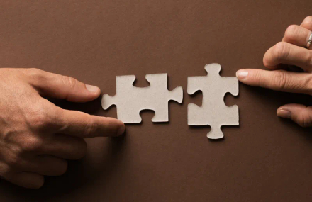 Hands assembling two jigsaw pieces.