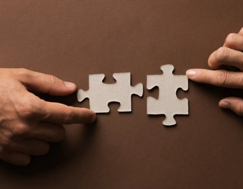 Hands assembling two jigsaw pieces.