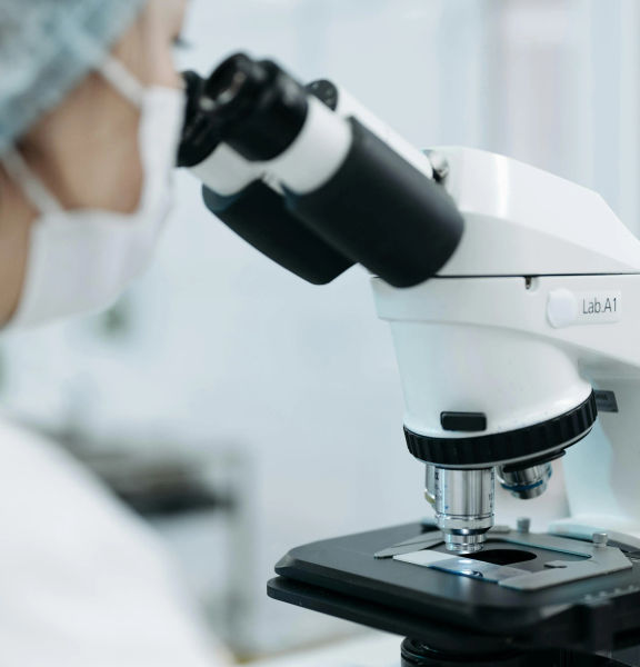 A person in a laboratory looking into a microscope.
