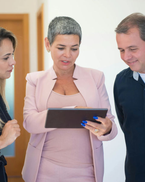 Three people talking over a tablet device.
