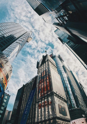 An image looking up at skyscrapers and the sky from the ground