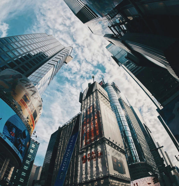 An image looking up at skyscrapers and the sky from the ground