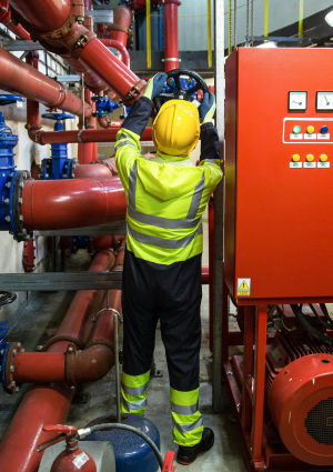 An image of a person in reflective high visibility clothing and a hard hat turning a large valve