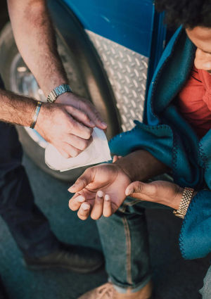 An image of a man with a hand injury being assited by someone else