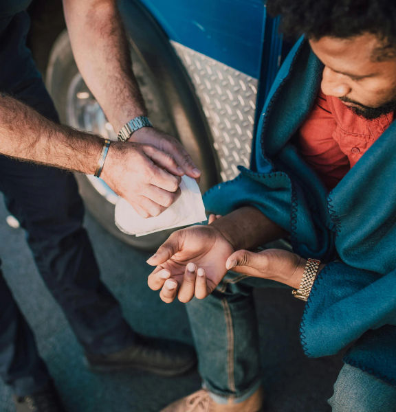 An image of a man with a hand injury being assited by someone else