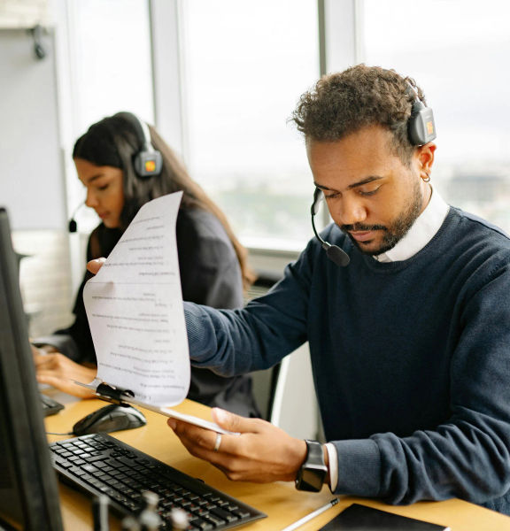 Two people at computers, wearing headsets.