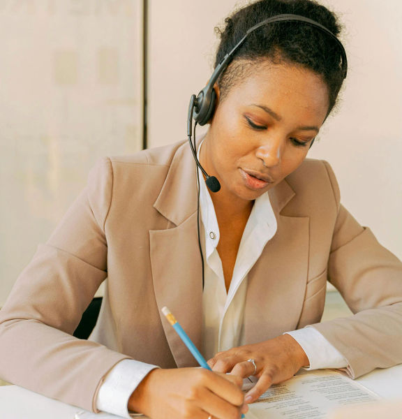 A woman wearing a headset taking notes.