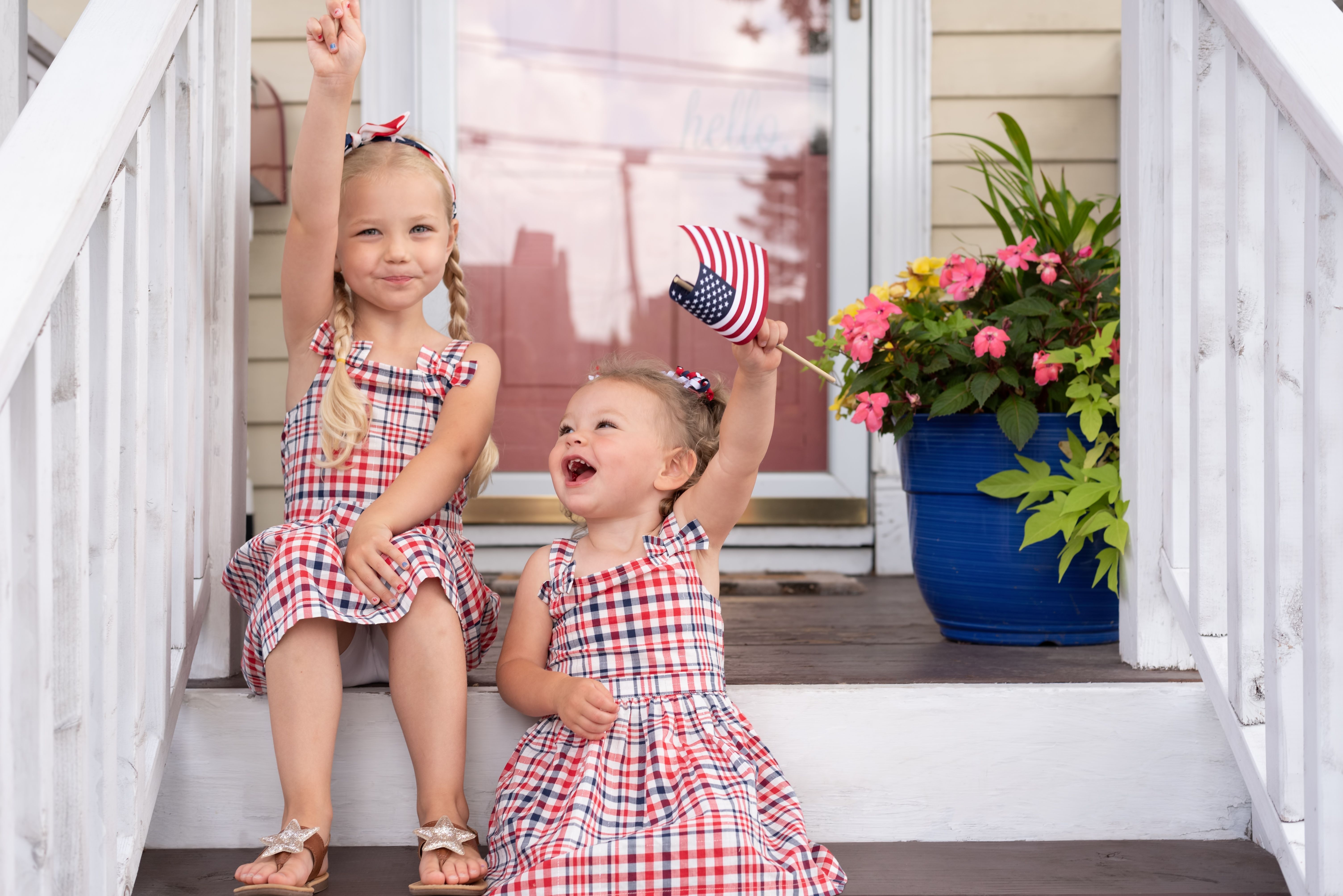 Two happy little girls waving flags on the fourth