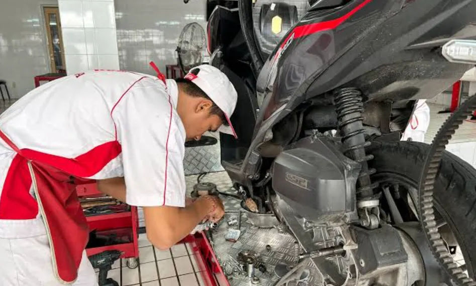 Mekanik sedang melakukan penggantian pelumas pada mesin motor