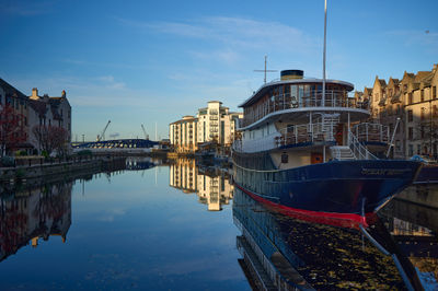 Water Of Leith Shore. A serene scene with a solitary boat on the water, emphasizing tranquility and space.