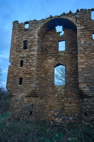 Saltcoats Castle, East Lothian, Gullane, Scotland. A serene landscape with a stone building, lush grass field, and intricate designs.