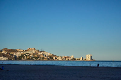 A scenic coastal town with a vibrant beach and colorful buildings under a blue sky. Captures the idyllic atmosphere of a relaxing seaside paradise.